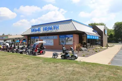 Front of the Amherstburg Home Health store on a sunny day, with mobility scooters parked along the walkway.